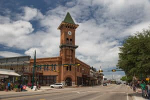 Main Street in Grapevine, TX featuring a historic red brick clock tower, well-kept greenery, and bustling street activity, exemplifying the city’s effective lawn fertilization practices.